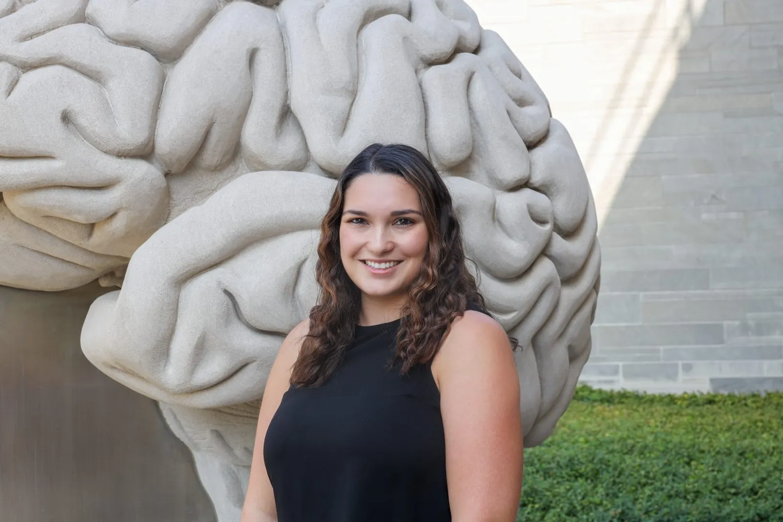Marianne Chirica standing in front of a large stone sculpture of a human brain